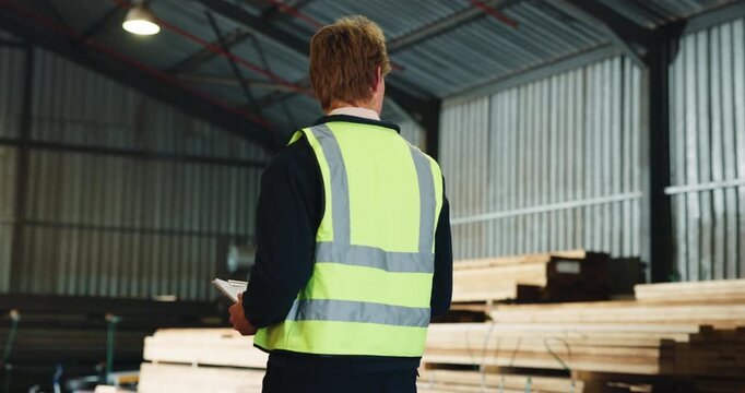 Man, carpenter or inspection with checklist in warehouse for wood production, logistics or distribution. Male person, walking and checking stock or inventory for timber storage or lumber supply chain