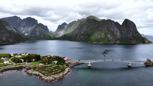 Aerial view of vehicle driving in Lofoten, steeply rising mountain landscape above ocean in Norway