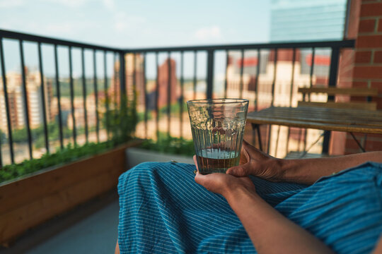 Hands holding a glass on a balcony with city skyline behind