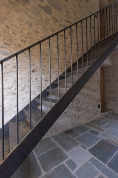 An iron staircase in an old house with stone walls and stone-slab floors.