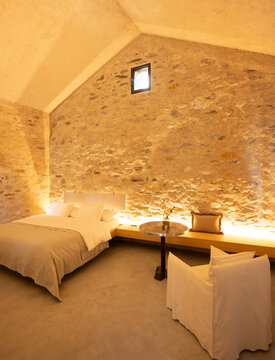 The interior of a beautiful bedroom with a very cosy atmosphere. The walls are made of stone and the room has a romantic feel. The bed is large and sleeps two people. It is a luxury flat.