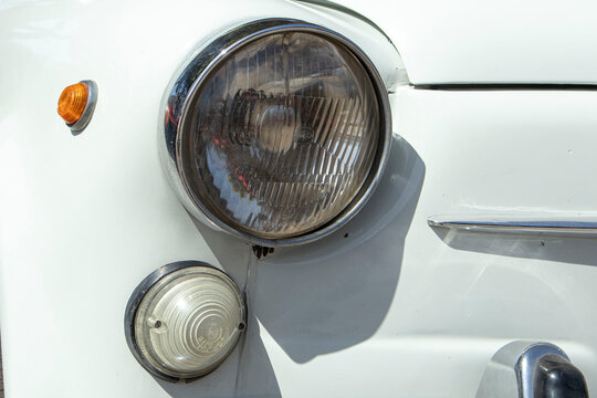 Tavernes Blanques, Spain - June 14, 2026. Close view of round chrome headlight and vintage bodywork of classic white SEAT at Spanish automotive exhibition