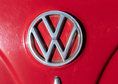 Tavernes Blanques, Spain - June 14, 2026. Round chrome Volkswagen badge logo on glossy red bodywork of vintage Beetle car captured in macro shot
