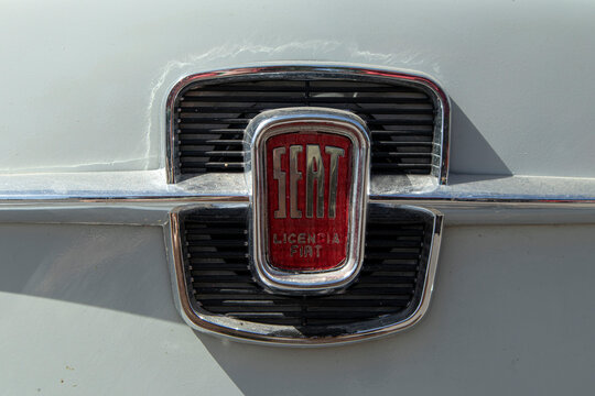 Tavernes Blanques, Spain - June 14, 2026. Macro close up of vintage red and chrome SEAT Licencia Fiat logo badge on classic vehicle grille in a restoration setting