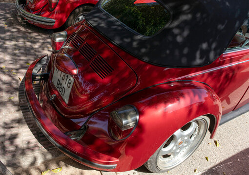 Tavernes Blanques, Spain - June 14, 2026. Classic Volkswagen Beetle shows rear view with engine lid and bumper in metallic red color on a sunny day