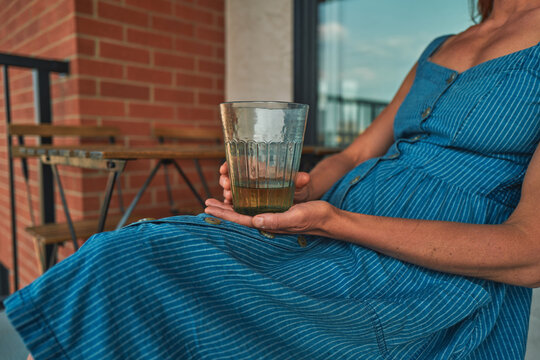 Woman in a striped dress holding a glass on an urban balcony