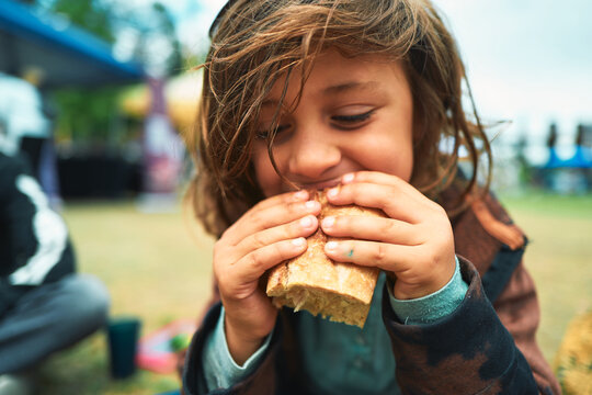 Young child biting into a ciabatta sandwich with both hands