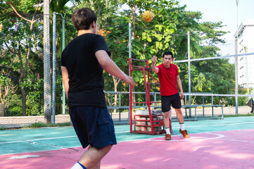 Obraz premium Focused male Thai Sepak takraw player, acting as the tekong or server, demonstrating intense concentration and mental focus on the outdoor court before delivering a serve