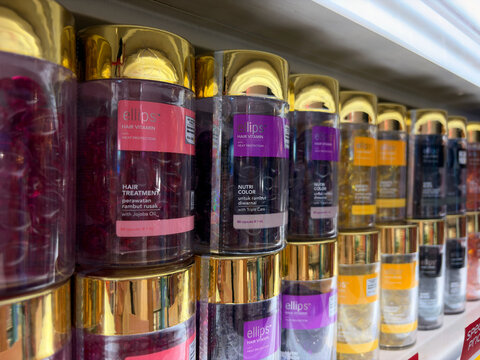 Bali, Indonesia - July, 15, 2026: A close-up of a shelf displaying colorful jars of skincare products. The jars feature various labels and vibrant colors like purple, pink, and orange