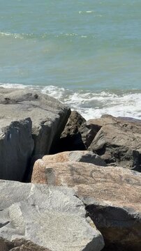 Rocky shoreline with ocean waves and blue sky, coastal landscape background