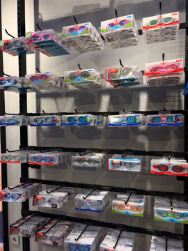 Bali, Indonesia - July, 15, 2026:A retail display featuring various colors and styles of swim goggles. The goggles are arranged neatly in packages on a black shelving unit. Bright colors dominate the 