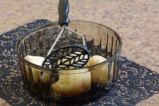 Potato's in a glass with potato masher.