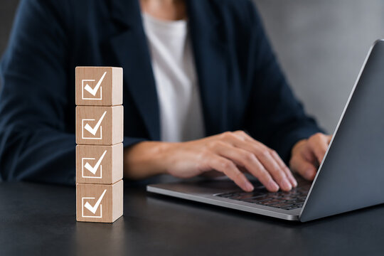 Businessman planning checklist using wooden cube with check marks, productivity goal setting and time management strategy concept for corporate success and effective work organization.