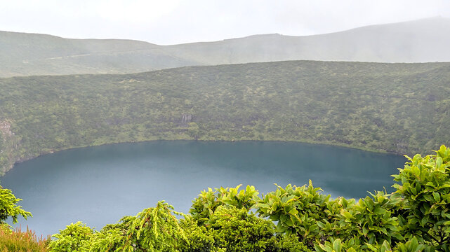 Volcanic crater lake Miradouro da Caldeira Negra e da Caldeira Comprida surrounded by green caldera in the Azores Portugal. Geological landscape concept for adventure tourism volcanic nature and Atlan