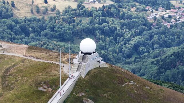 Aerial view of the Grand-Ballon radar station atop the mountain peak surrounded by lush forests and rolling hills in Soultz-Haut-Rhin, Grand Est, France.
