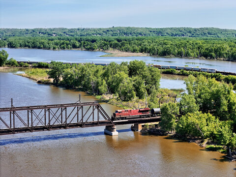  Locomotive pulling freight about to cross a Steel Truss Bridge Over the Mississippi River