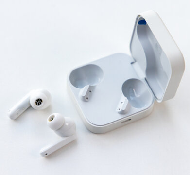 Modern wireless earbuds with charging case on white background