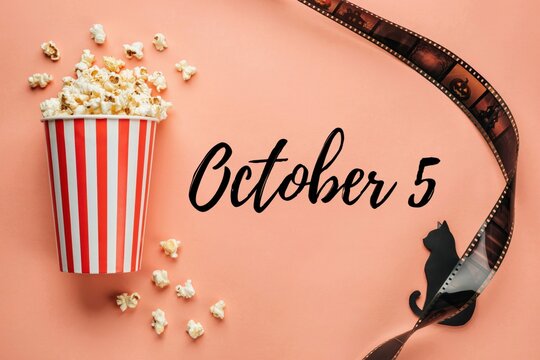 October 5 Movie Night Concept with Popcorn Bucket and Film Strip on Pink Background