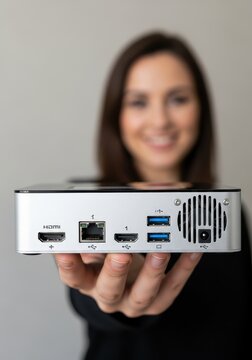 Close-up of a Small Silver Mini Computer Held by a Woman, Featuring HDMI, Ethernet, and USB Ports