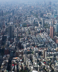 Fototapeta premium Vertical aerial view of Taipei city from Taipei 101 observatory, showing densely packed residential and commercial buildings stretching across the Taiwanese capital into the hazy distance.