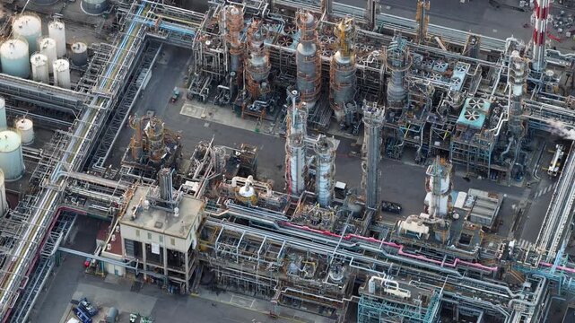 Aerial view of an industrial refinery complex featuring complex pipe networks, tall distillation towers, and storage tanks in Bantzenheim, Grand Est, France.