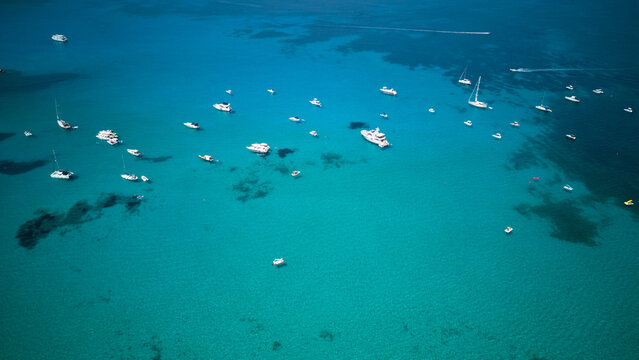 Numerous yachts and motorboats are anchored in the stunning shallow turquoise waters of san vito lo capo, sicily, creating a vibrant scene of summer vacation and marine leisure