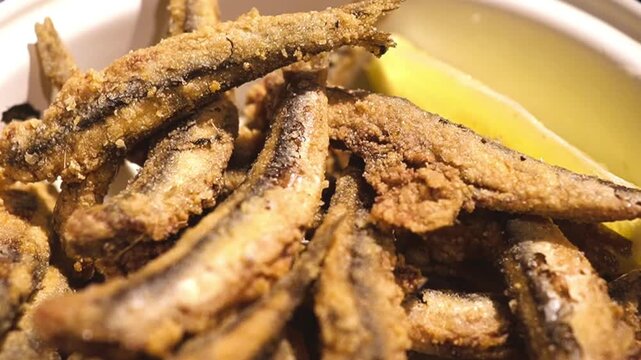 Tilt down shot of crispy fried boquerones with lemon, traditional spanish tapas