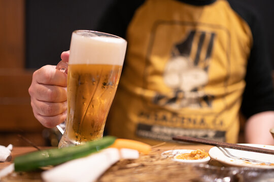 居酒屋で冷えた生ビールを持つ男性の手元