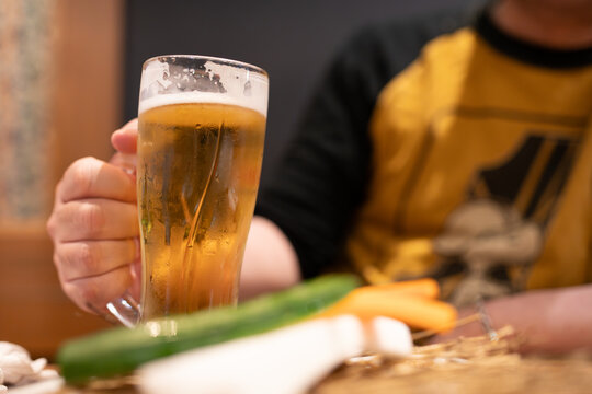 居酒屋で冷えた生ビールを持つ男性の手元