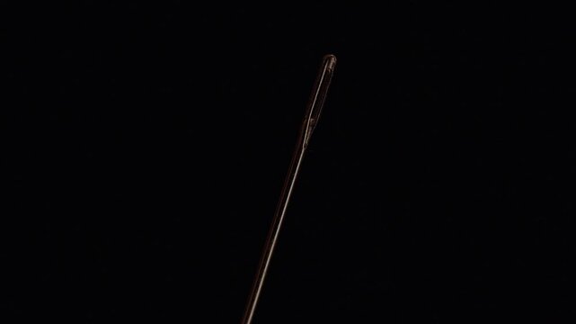 Sewing Needle Eye Shown in Extreme Macro Against a Black Background, Highlighting Precision and Textile Craft