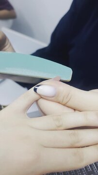 Manicurist filing client nails with nail file close up 9:16 vertical, beauty salon manicure treatment concept