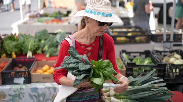 A woman smiles as she selects fresh vegetables and fruits at a market in Sonoma, California on a bright morning.