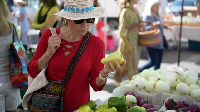 A senior woman smiles while choosing fresh fruits and vegetables at the farmers market in Sonoma California during the morning.