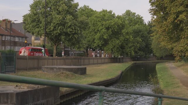 Footbridge Railing Over Canal with Red Bus Passing Behind