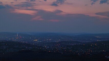 Fototapeta premium Panoramic nightfall view of Iasi city lights glowing under a dramatic dusk sky, taken from Repedea Hill, Romania. Ideal for landscape themes.