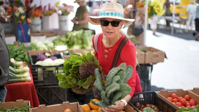 Woman buys fresh kale at Sonoma Farmers Market on a sunny morning filled with cheerful shoppers.
