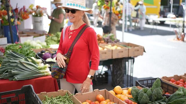 Woman smiles while selecting fruits and vegetables at the Sonoma Farmers Market in California during a bright morning.
