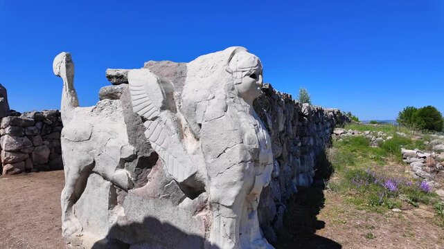Two carved stone sphinxes guard the ancient entrance portal of the Sphinx Gate, set within stone walls at Hattusa.