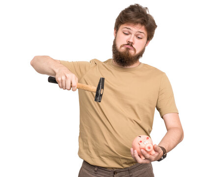 Bearded young man trying to smash a piggy bank with a hammer, expressing reckless spending, financial stress, debt or poor money management.