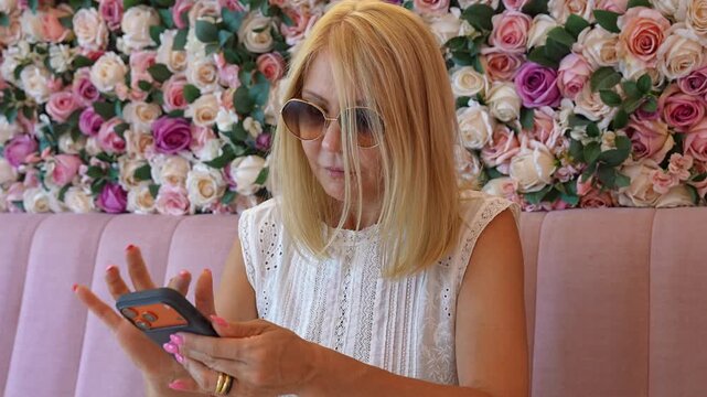 Elegant blonde woman texting on her smartphone in a cafe