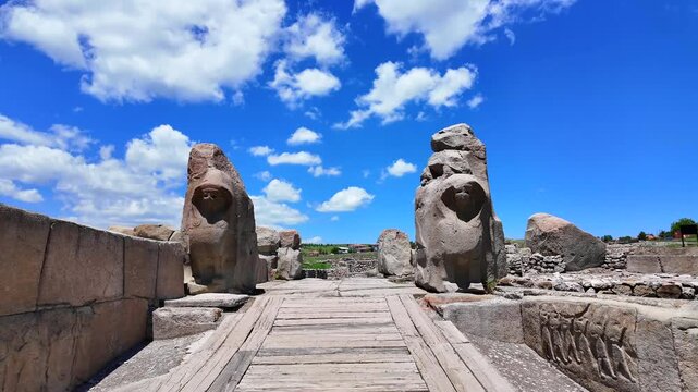 Two massive stone sphinx statues flank the entrance gate of the ancient Hittite site Alacah&ouml;y&uuml;k beneath a blue sky.