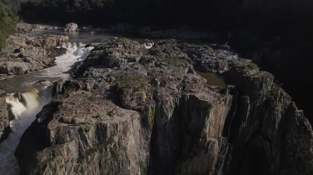 Aerial view of the rocky Barron Falls gorge with cascading water and lush tropical rainforest surroundings in Kuranda, Queensland, Australia.