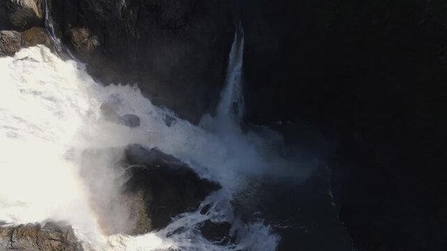 Aerial view of the powerful Barron Falls cascading down rocky cliffs surrounded by dense tropical rainforest in Kuranda, Queensland, Australia.