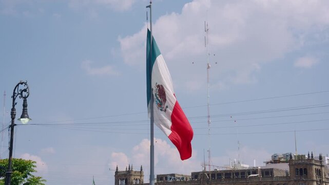 Mexican flag waving in the wind with the mexico city skyline and a blue sky in the background