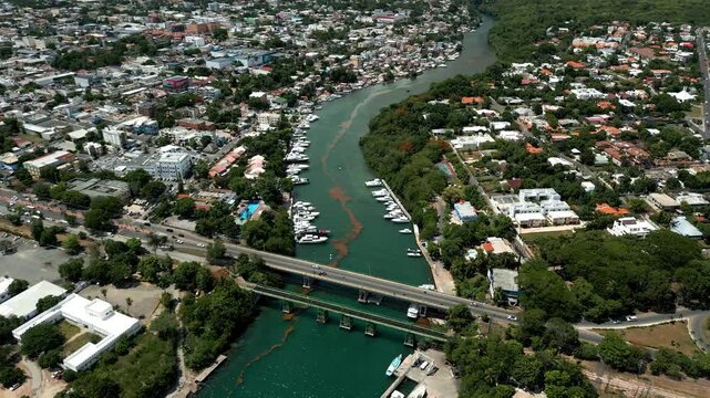 Aerial view of the Chavon River flowing through the city with boats docked at the marina and a bridge crossing the water in La Romana, La Romana Province, Dominican Republic.