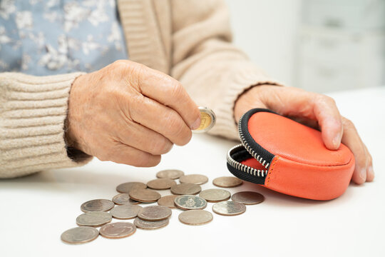 Asian senior or elderly old lady woman holding counting coin money in purse. Poverty, saving problem in retirement.