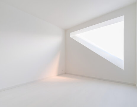Espacio vac&iacute;o con luz natural entrando por una ventana en un ambiente blanco y claro en un edificio moderno