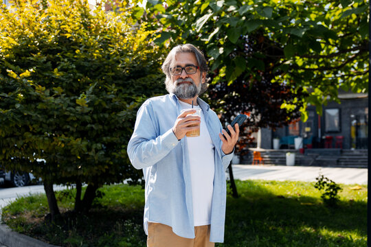 Senior man enjoying coffee and smartphone outdoors