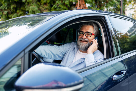 Senior man driving car talking on smartphone