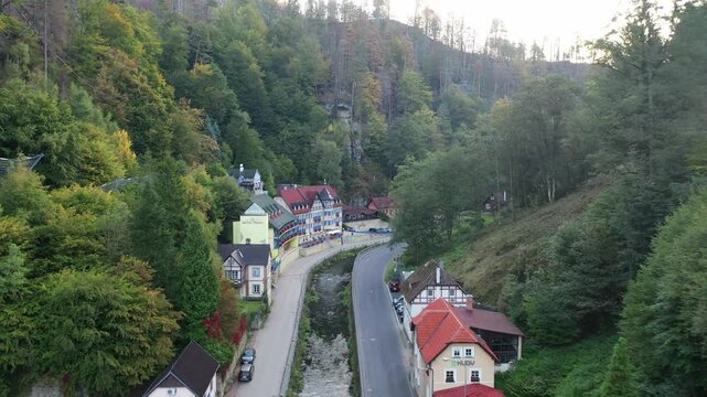 Aerial view of the village nestled in a lush forested valley with a river and road in Hrensko, Usti nad Labem Region, Czechia.
